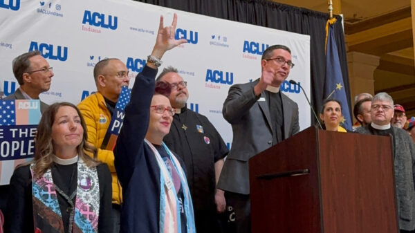 A crowd of people standing in front of a banner that features the ACLU of Indiana logo.