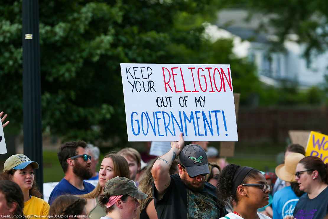 A protestor holds a sign reading "Keep Your Religion Out of My Government" during a rally at Memorial Park in Danville, Pennsylvania.