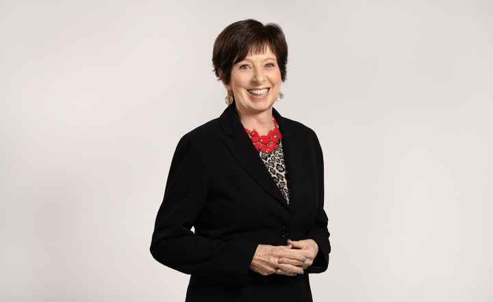 Coach McGraw poses for a headshot in a black blazer and red necklace. 