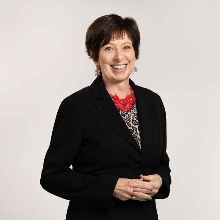 Coach McGraw poses for a headshot in a black blazer and red necklace. 